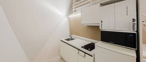 Una cocina moderna con un refrigerador Samsung integrado, un lavamanos y un calendario colgado en la pared.