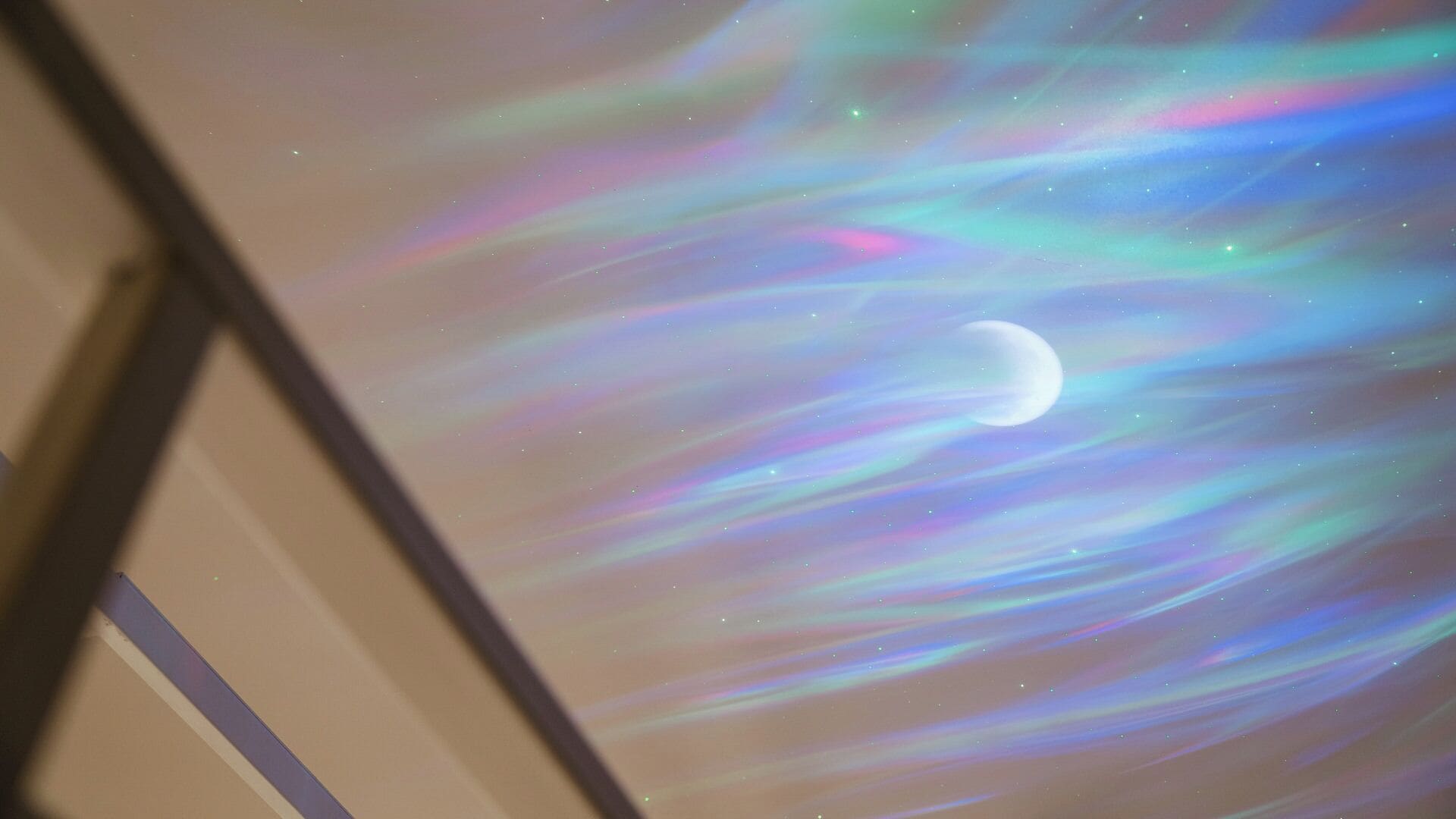 A projection of a celestial scene with a moon and stars on a ceiling.