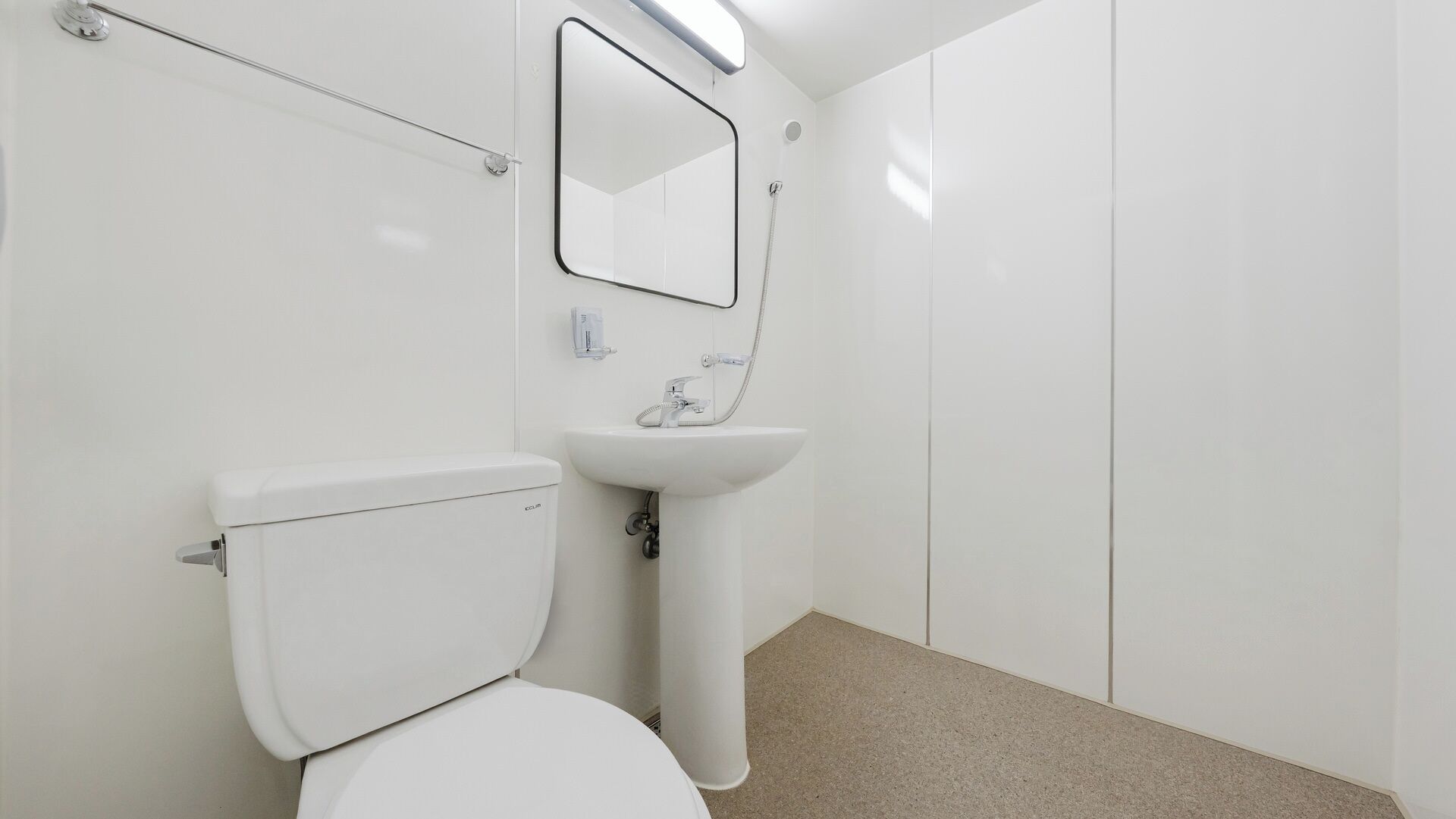 A bathroom with a toilet, sink, and mirror.