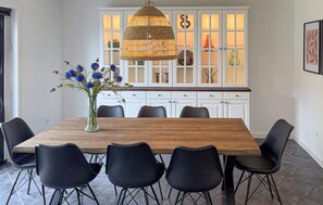 Ein Essbereich mit einem Holztisch, schwarzen Stühlen, einer Blumenvase und einer Pendelleuchte.