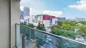 A cityscape with a building featuring large advertisements, a clear sky, and surrounding greenery. - Yumi Apt Foshan Zumiao Metro Station (Foshan)