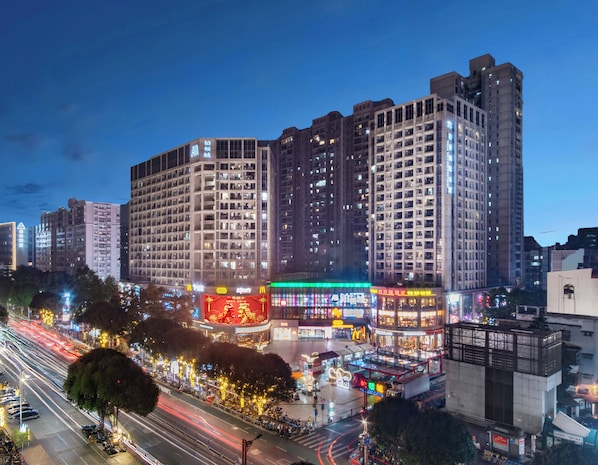A multi-story hotel with a modern architectural design, featuring a prominent entrance and a large illuminated sign.