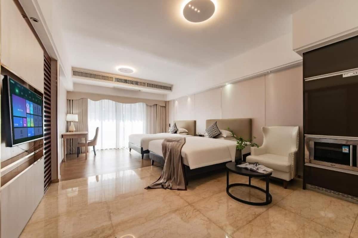 A hotel room with a bed, a chair, a TV, a desk, and a dining area.