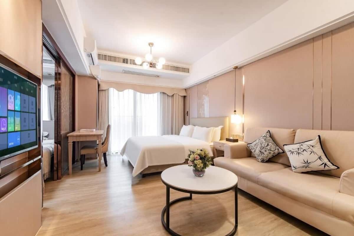 A hotel room with a bed, a sofa, a coffee table, a TV, and a desk.