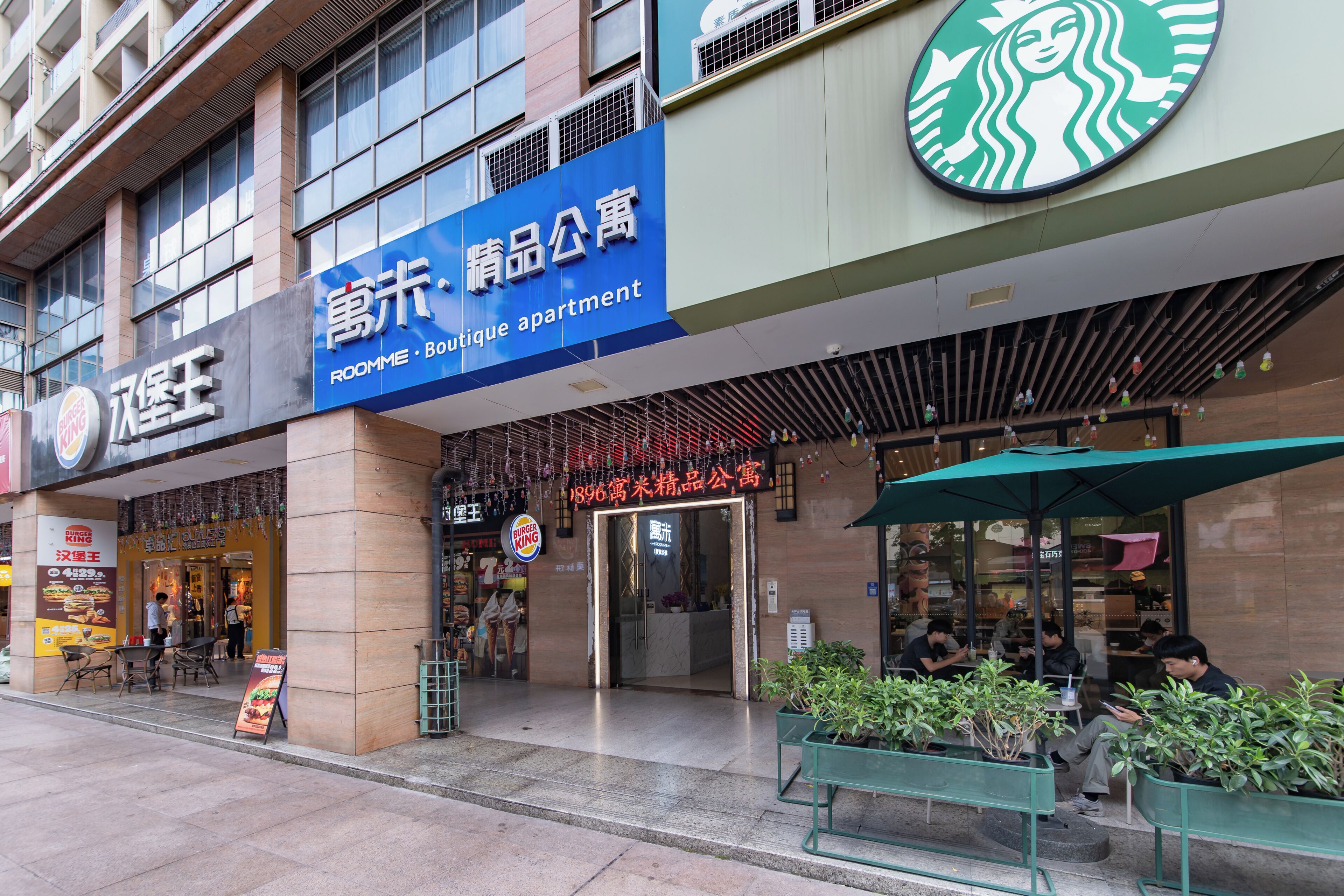 A building with a sign for 'Roomme Boutique Apartment' and a Starbucks logo.
