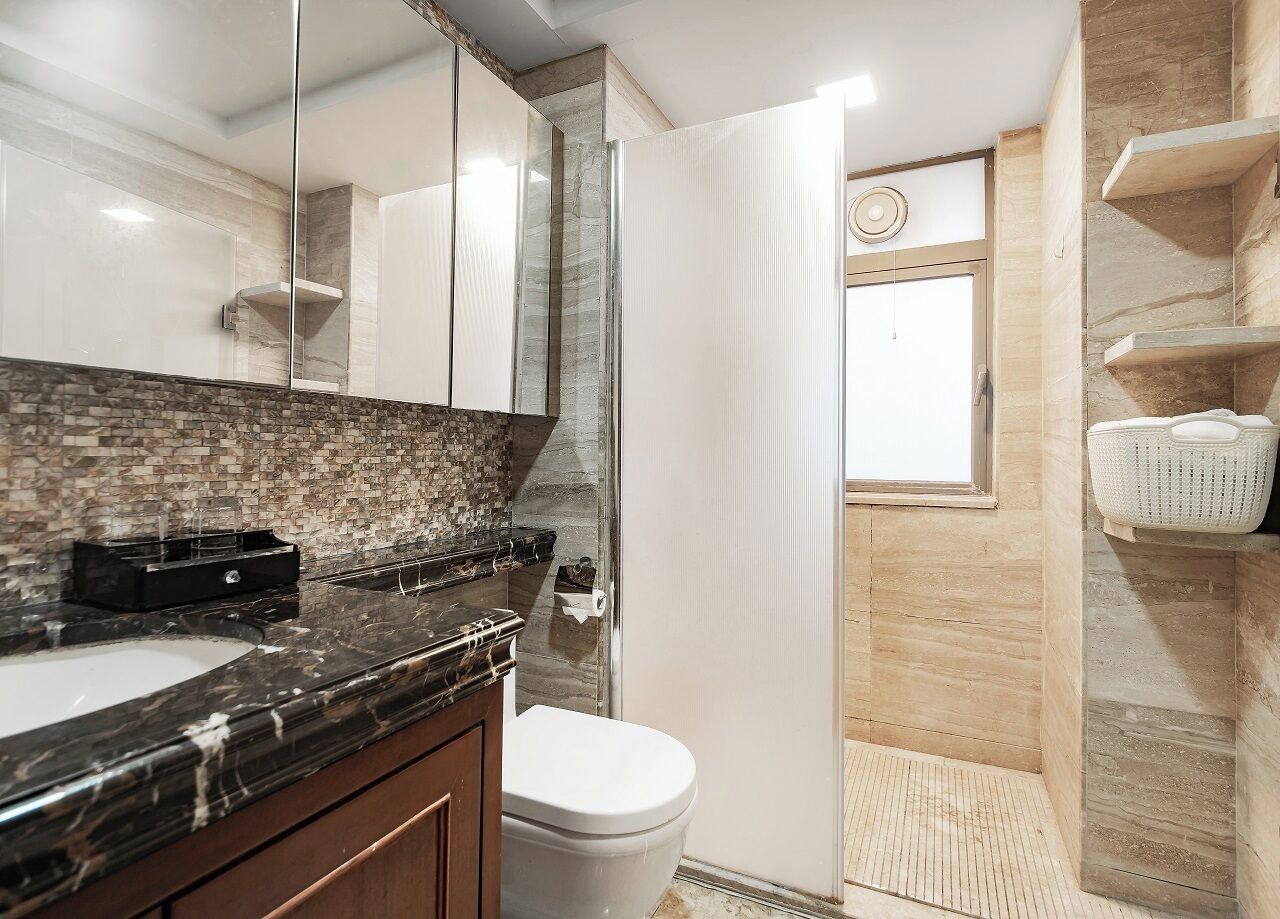 Une salle de bain avec un lavabo en marbre, des toilettes, une douche en verre et un porte-serviettes.