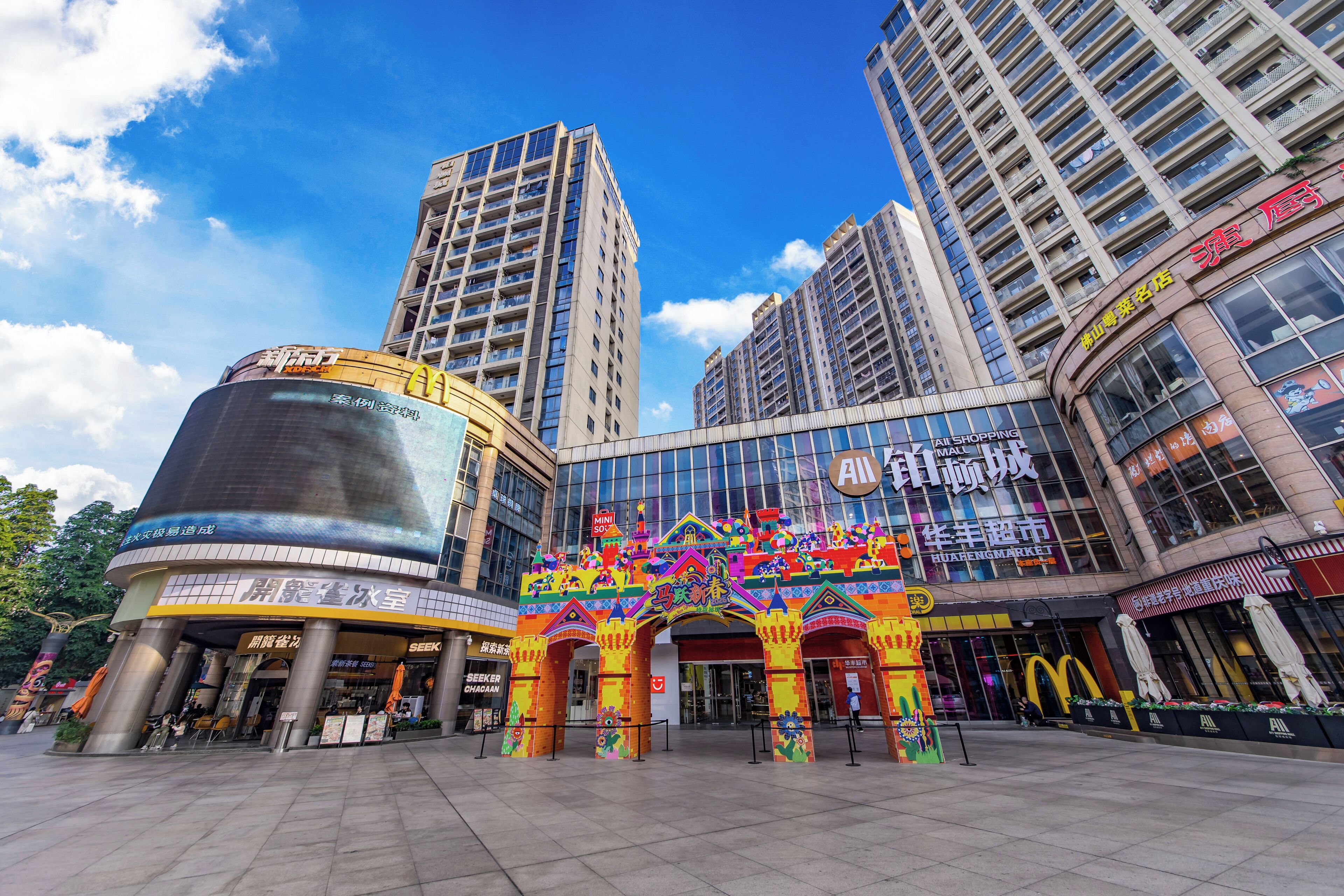 A multi-story building with a large glass facade, a colorful entrance archway, and a McDonald's sign.