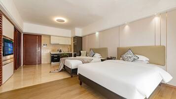 A hotel room with two beds, a desk, and a television.