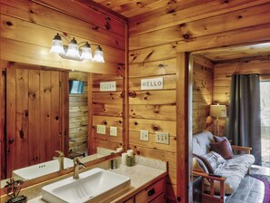 Ein Holzblock-Interieur mit Badezimmer, Bett und einem 'HELLO'-Schild an der Wand.