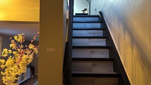 Un escalier avec des marches en bois et des rampes noires, menant à l’étage supérieur.