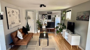 Un salon moderne avec un canapé en cuir marron, une table basse et un téléviseur posé sur un meuble blanc.