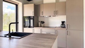 Una cocina moderna con horno integrado, cafetera y pileta.