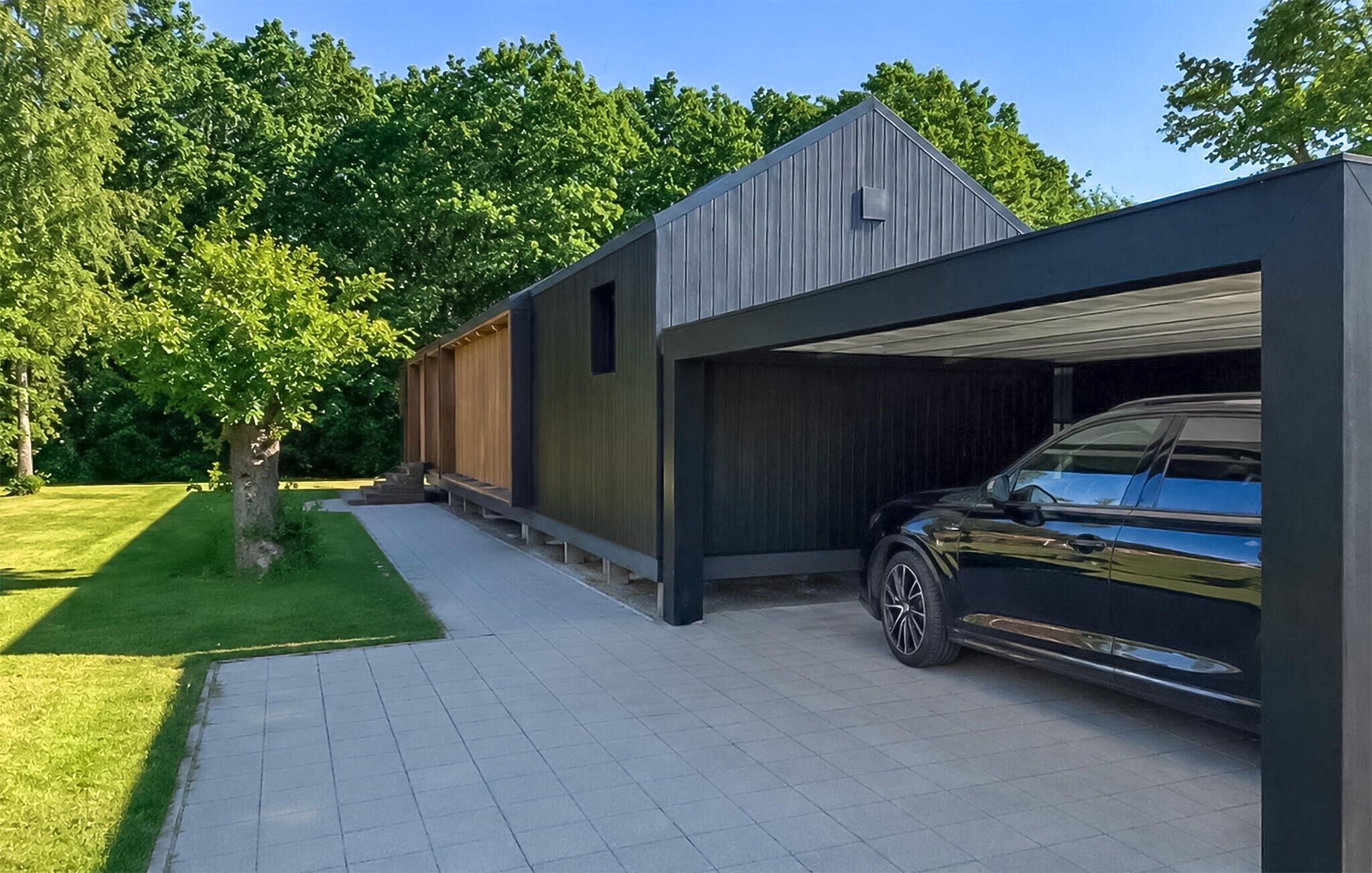Een modern gebouw met een garage en een geparkeerde auto.