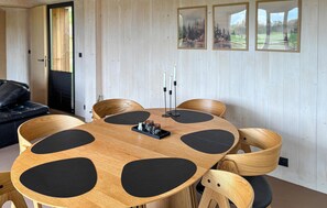 A round wooden table with black circular cutouts, surrounded by wooden chairs with black cushions. - Lovely home in Sunds with WiFi (Sunds)
