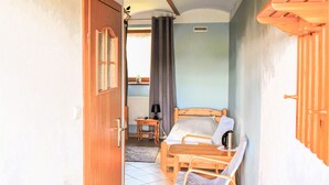 Una habitación con cama, una mesita, una silla y una ventana con cortinas.