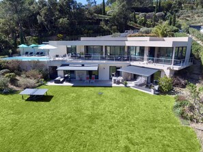 Ein modernes, zweistöckiges Haus mit Pool, Sitzgelegenheiten im Freien und einem gepflegten Rasen.