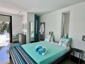 Ein modernes Schlafzimmer mit einem großen Bett, einem Badezimmer mit Dusche und Blick ins Freie.