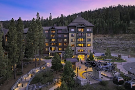 A multi-story hotel with a stone facade, multiple balconies, and a central entrance.