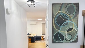 Ein Flur mit Marmorboden, einem modernen abstrakten Gemälde und einer Vase mit Zweigen.
