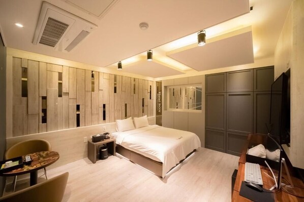 Una habitación de hotel moderna con cama, escritorio, silla y armario empotrado.