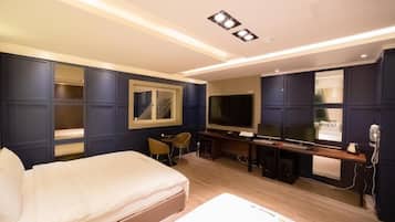 Una habitación de hotel con cama, escritorio, televisor y espejo.