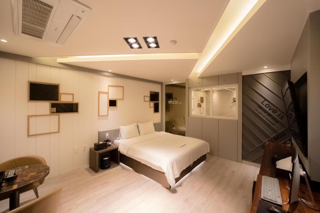 Un dormitorio moderno con cama, mesitas de noche, escritorio, silla, televisor y armario.