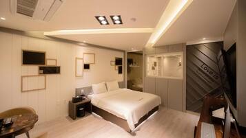Un dormitorio moderno con cama, mesitas de noche, escritorio, silla, televisor y armario.