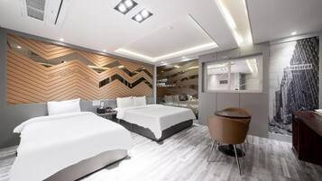 A modern hotel room with two beds, a seating area, a mirror, and a cityscape mural.
