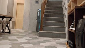 Uma escadaria leva a um patamar com guarda-corpo de madeira, uma mesa com cadeiras e uma televisão em um suporte.