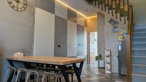 Um interior moderno com uma mesa e cadeiras de madeira, um relógio de parede e uma escadaria.
