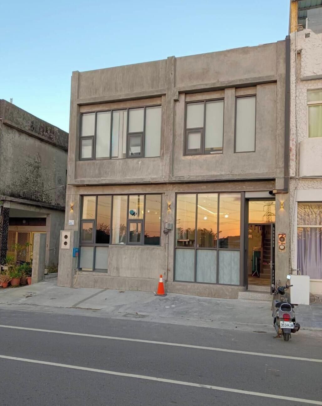 A two-story building with large windows, a motorcycle parked in front, and a visible door.