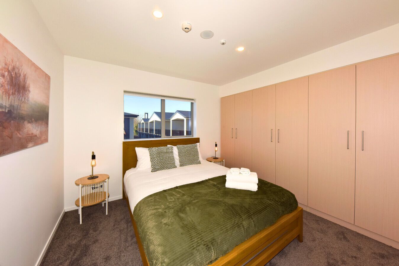 A bedroom with a bed, a nightstand, a window, and a wardrobe.
