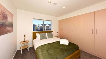 A bedroom with a bed, a nightstand, a window, and a wardrobe.