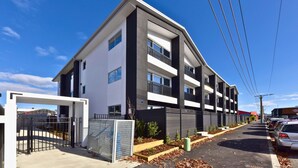 A modern multi-story building with a flat roof, large windows, and a gated entrance. - Spacious Bath Street Two Bedroom Retreat (Christchurch)