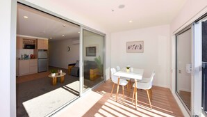 A modern interior with a dining area, kitchen, and sliding glass doors leading to a balcony. - Spacious Bath Street Two Bedroom Retreat (Christchurch)