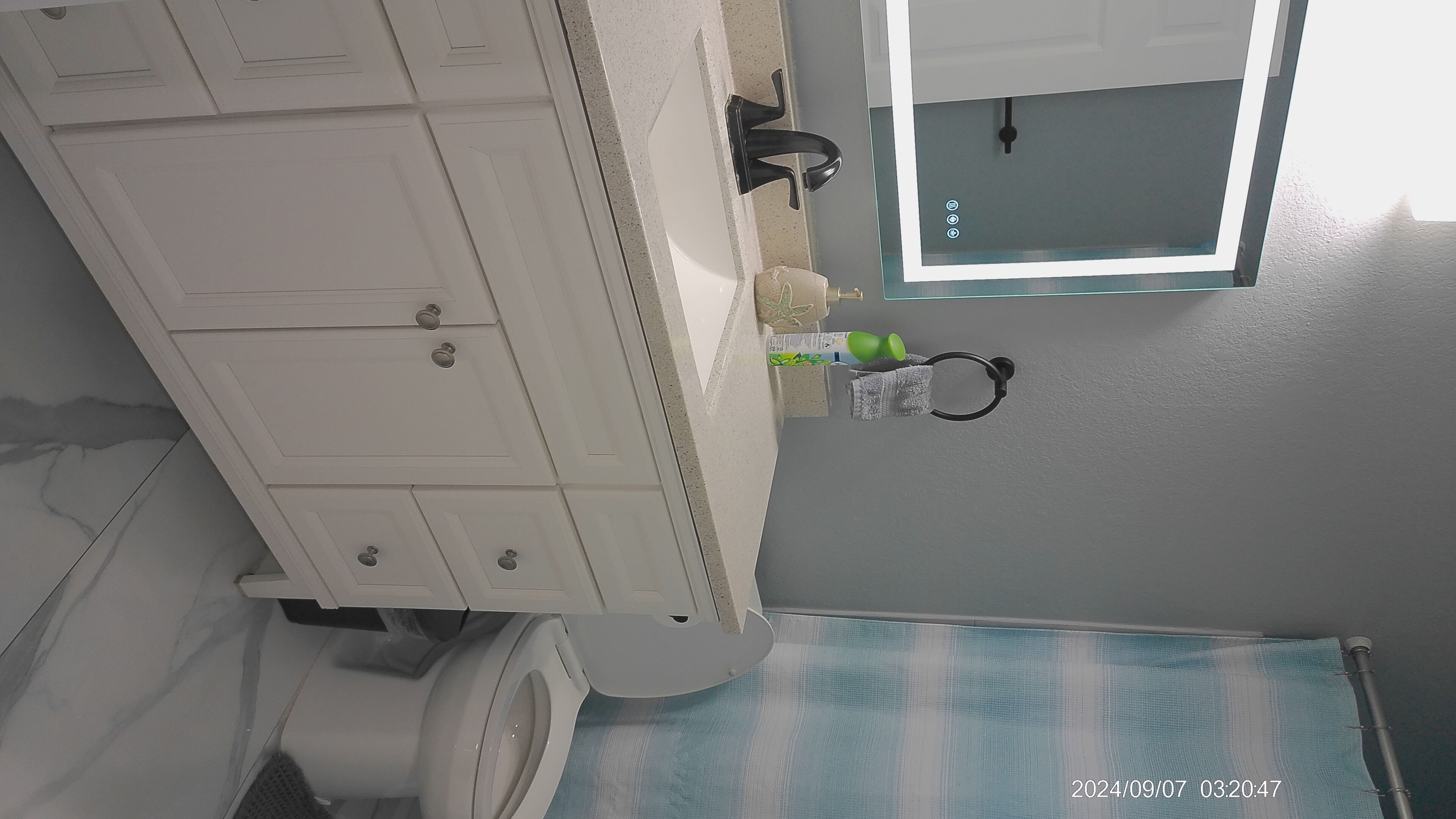 A bathroom with a white vanity, a mirror, and a toilet.
