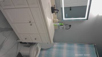 A bathroom with a white vanity, a mirror, and a toilet.