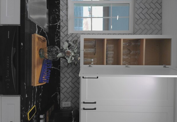Una cocina con salpicadero de encimera con motivo de espiga, una ventana sobre el fregadero y un armario de madera con un cartel que dice 'WELCOME'.