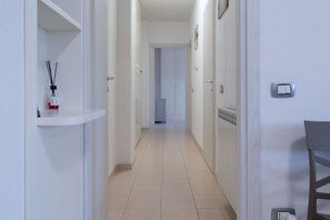 Ein Flur mit einem weißen Regal, einem Heizkörper und einer Tür zu einem weiteren Zimmer.