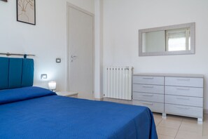 Ein Schlafzimmer mit einem Bett, einem Schminktisch, einem Heizkörper und einer Tür.