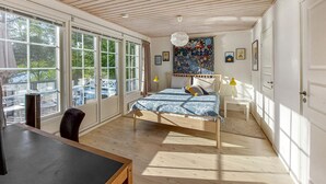 Ett sovrum med en säng, ett skrivbord, en stol, ett fönster och en dörr.