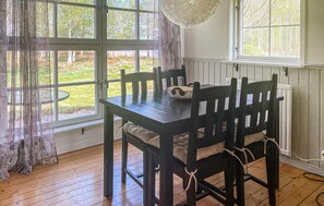 A dining table with chairs, a window with curtains, and a view of greenery outside. - 1 bedroom nice home in Växjö (Växjö)