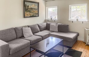 A living room with a sectional sofa, a glass coffee table, and two windows with blinds. - 1 bedroom nice home in Växjö (Växjö)