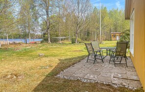 A patio with a table and chairs, a small shed, and a view of a lake and trees. - 1 bedroom nice home in Växjö (Växjö)