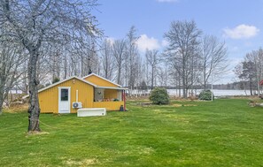 A yellow cabin with a porch, surrounded by a grassy yard and trees. - 1 bedroom nice home in Växjö (Växjö)