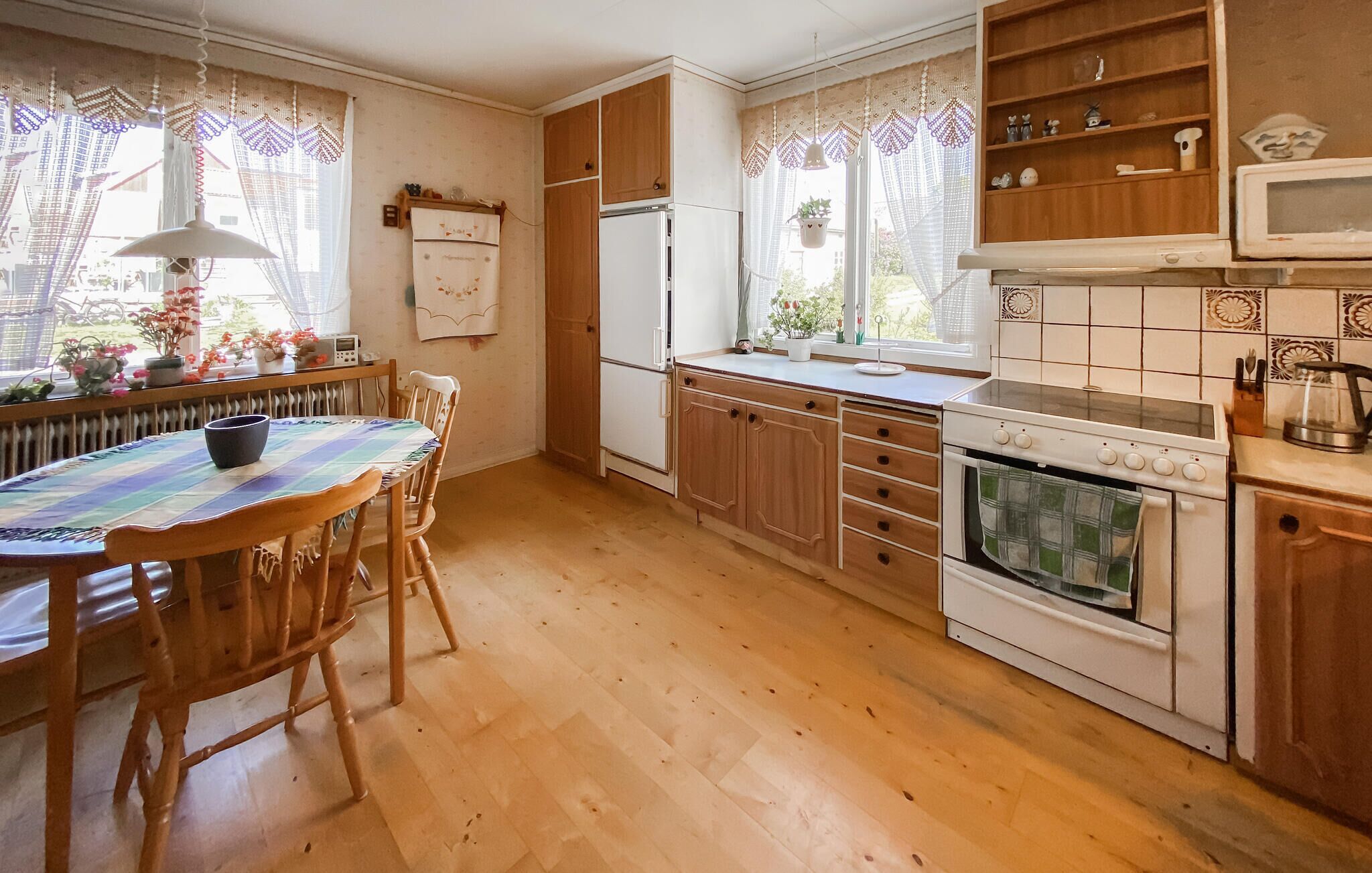 Une cuisine avec des meubles en bois, une table à manger avec des chaises, un réfrigérateur, un four et un four à micro-ondes.