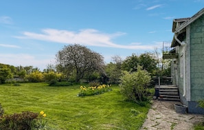 A grassy yard with a tree, a building with a staircase, and a metal fence. - 3 bedroom nice home in Borgholm (Borgholm)