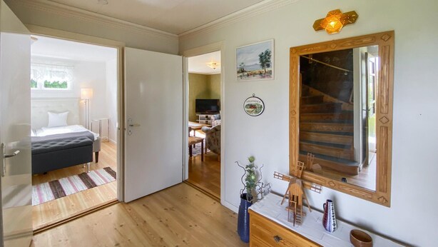 Une chambre à coucher comprenant un lit, une commode, un miroir et une porte donnant sur une autre pièce.