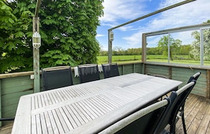 An outdoor patio with a wooden table and chairs, a hanging lantern, and a view of a green landscape. - 3 bedroom nice home in Borgholm (Borgholm)