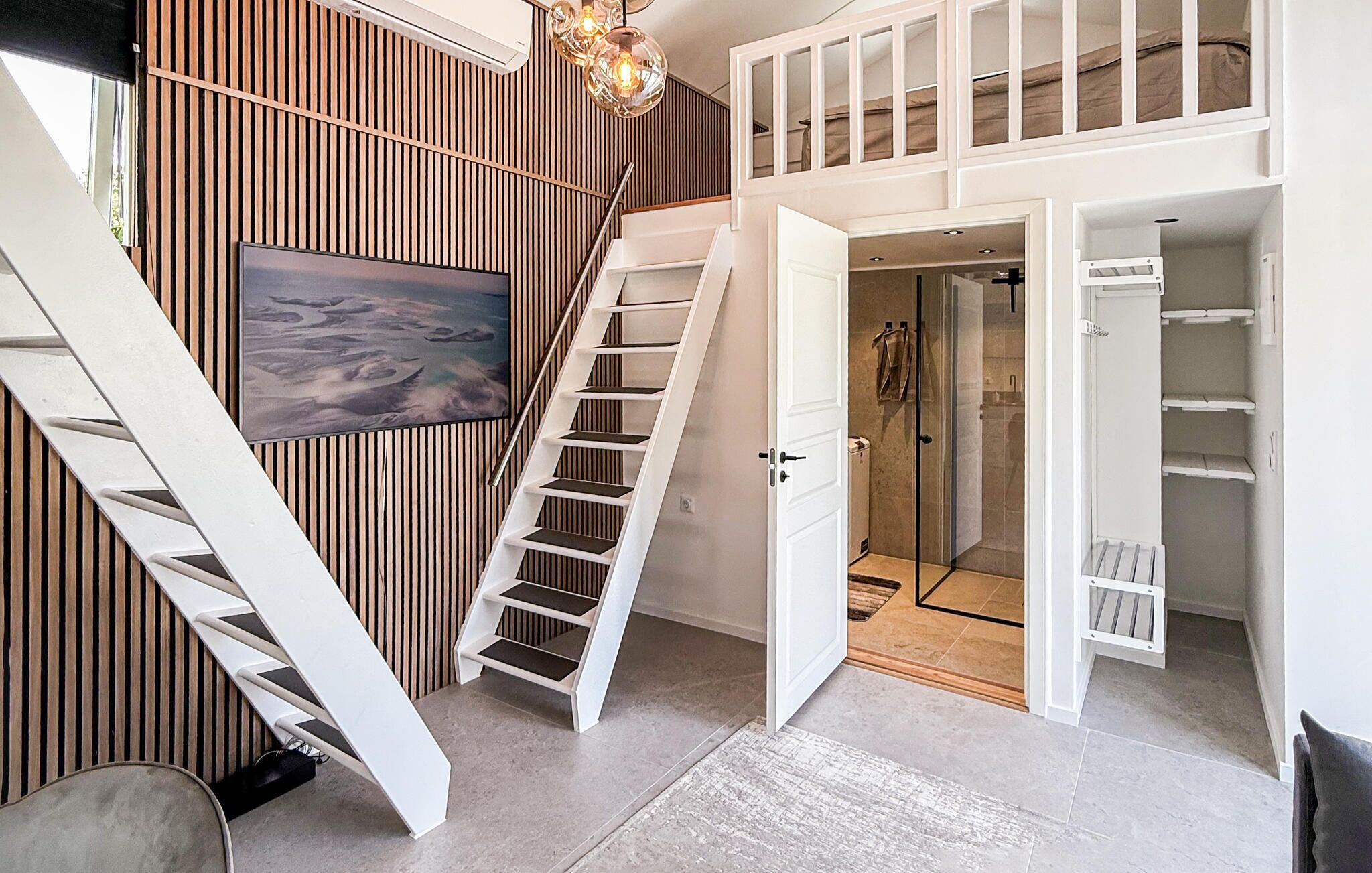 A modern interior with a staircase, a glass shower, and a mounted artwork.